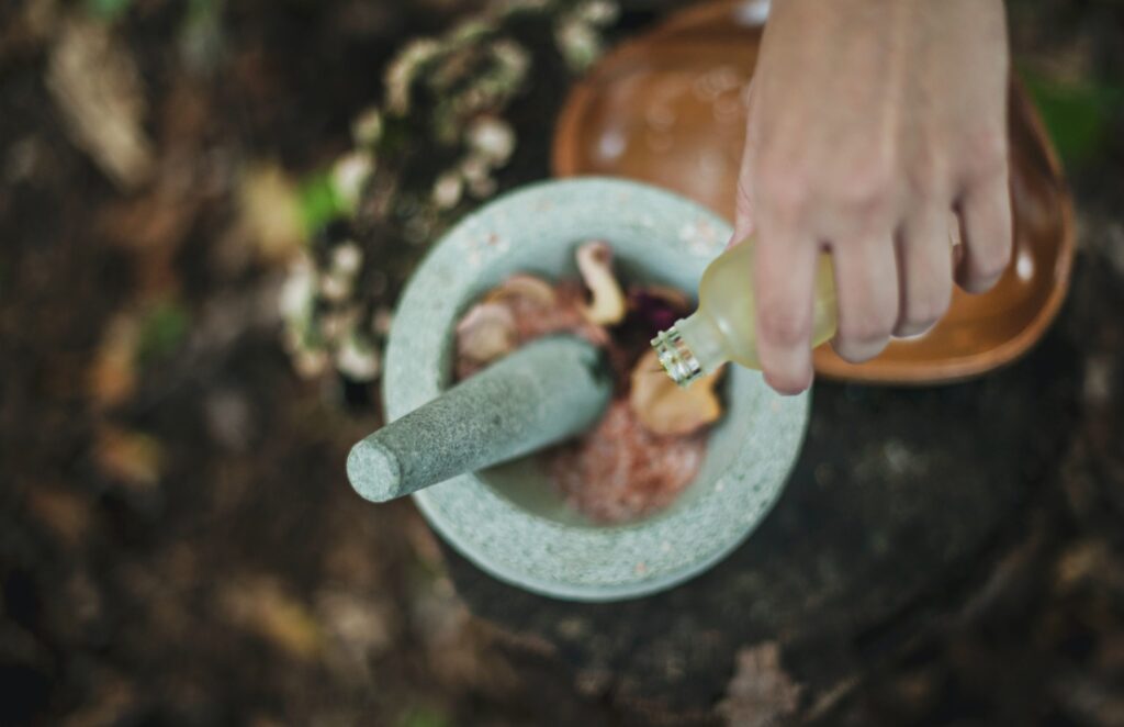 A hand pouring some liquid into a mortar and pestle. Probably making a potion of healing. One can never have too many potions of healing.
