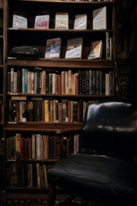 a bookshelf full of books with a leather chair next to it. Looks cozy.