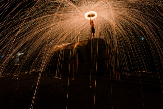 a person atop a structure with light and sparks flying away from them.