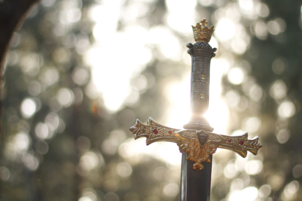 a sword decorated with gold and rubies. The sunlight glowing behind it.
