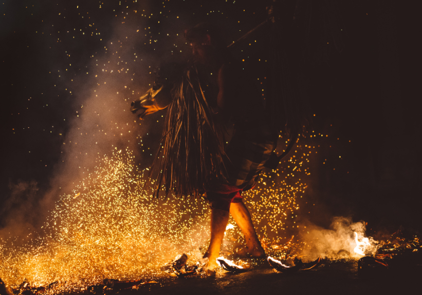 A person walking through fire while sparks fly all around them.