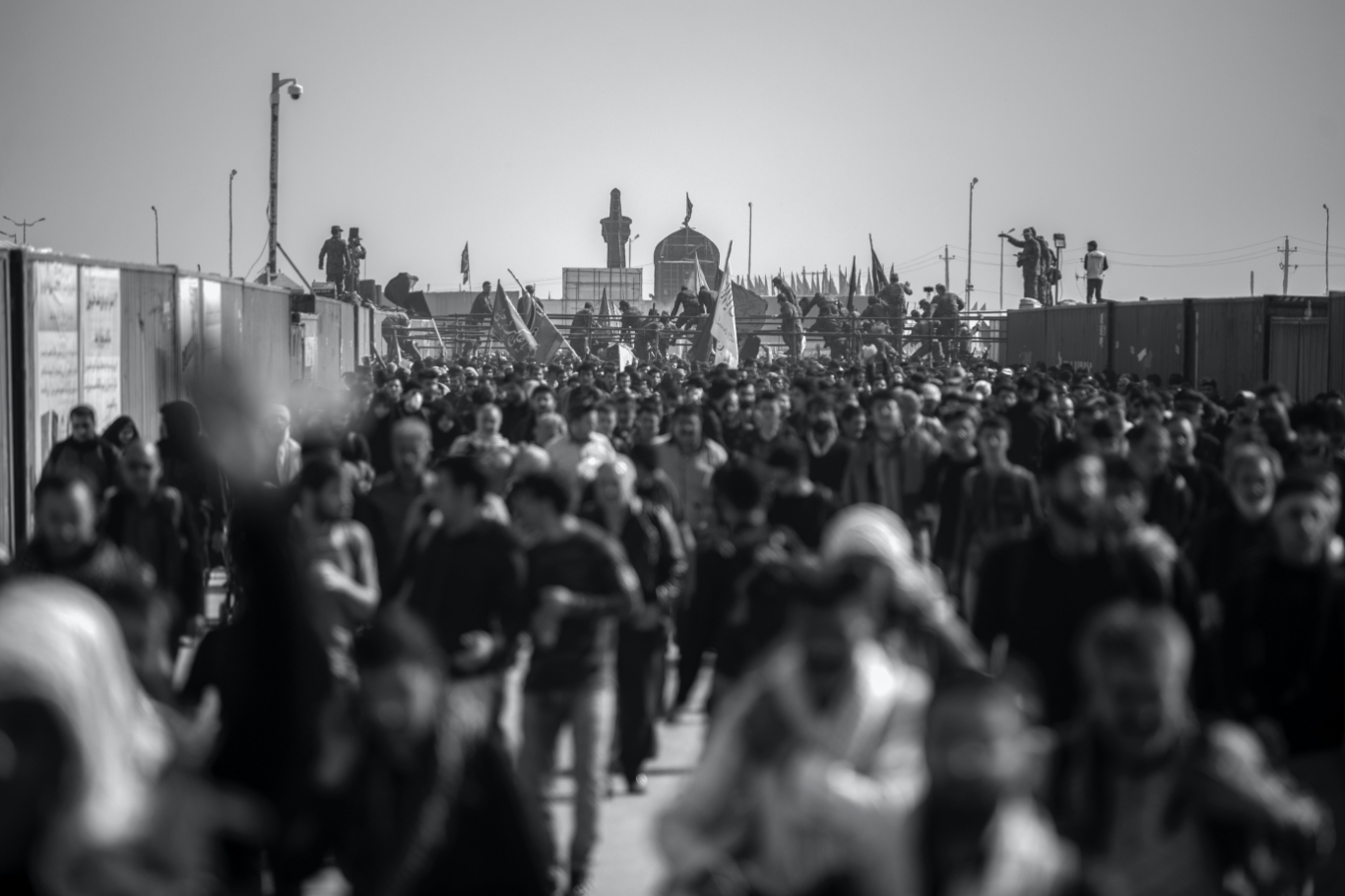 A crowd moving about on a street with a black and white filter.