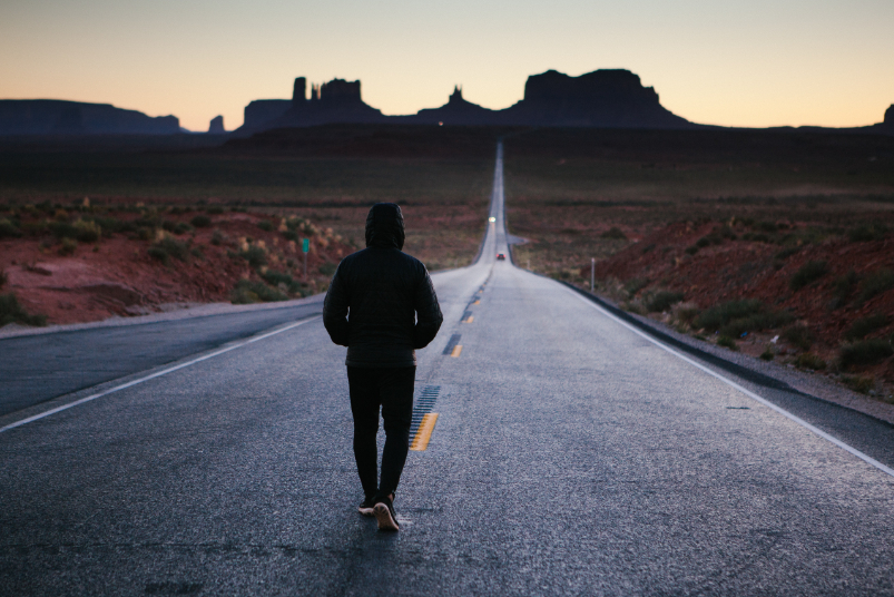 A single person walking down a two-lane highway. One could even say he is walking a lonely road on the boulevard of broken dreams.
