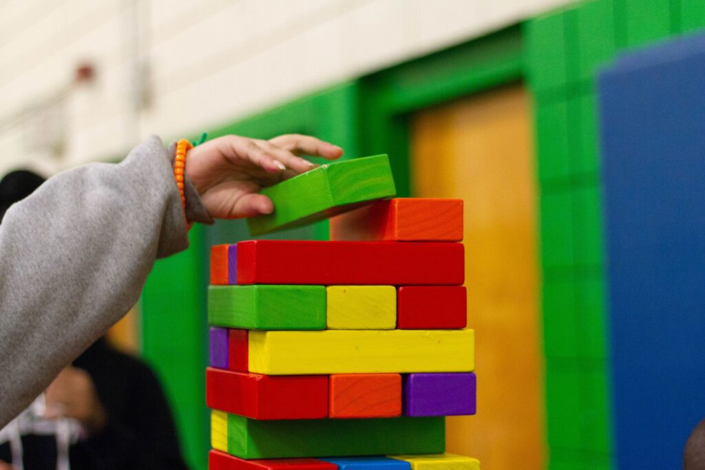 Child stacks a green block on a tower