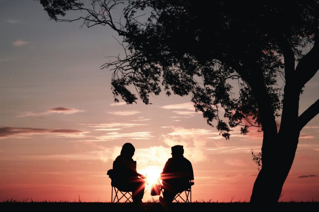 two people sitting before a sunset having conversations about story themes