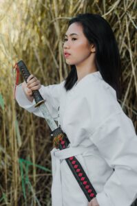 A person in white drawing a katana from its sheath 