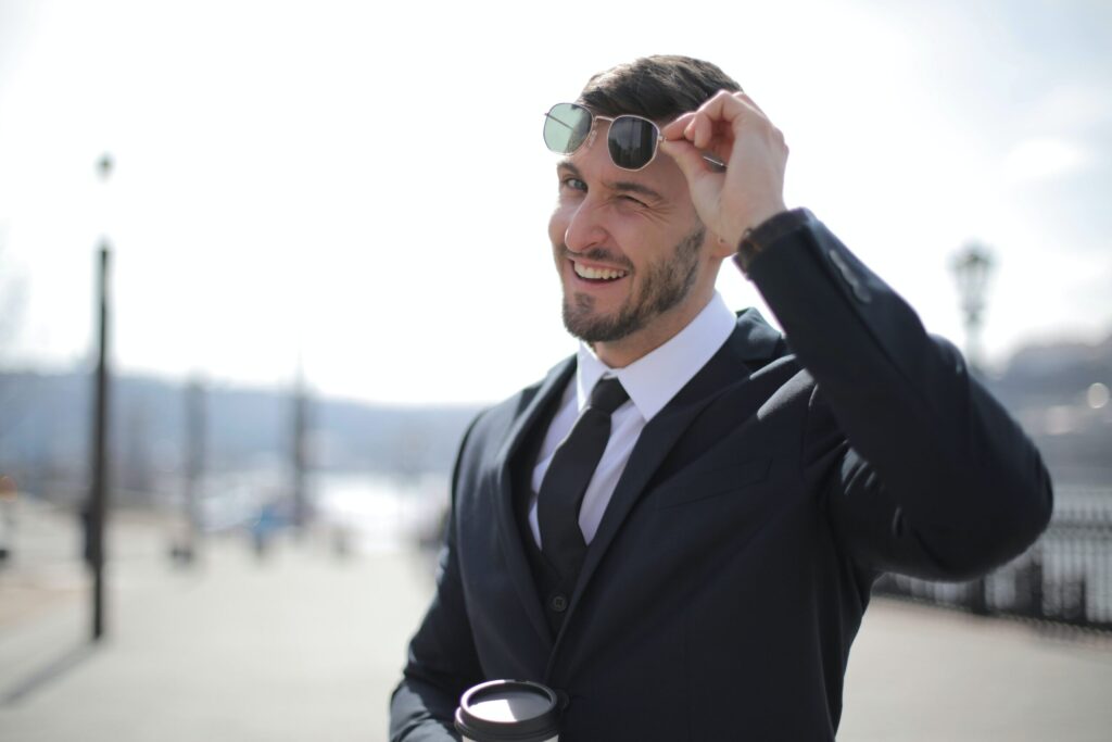 Person in suit lifting up glasses to show a wink