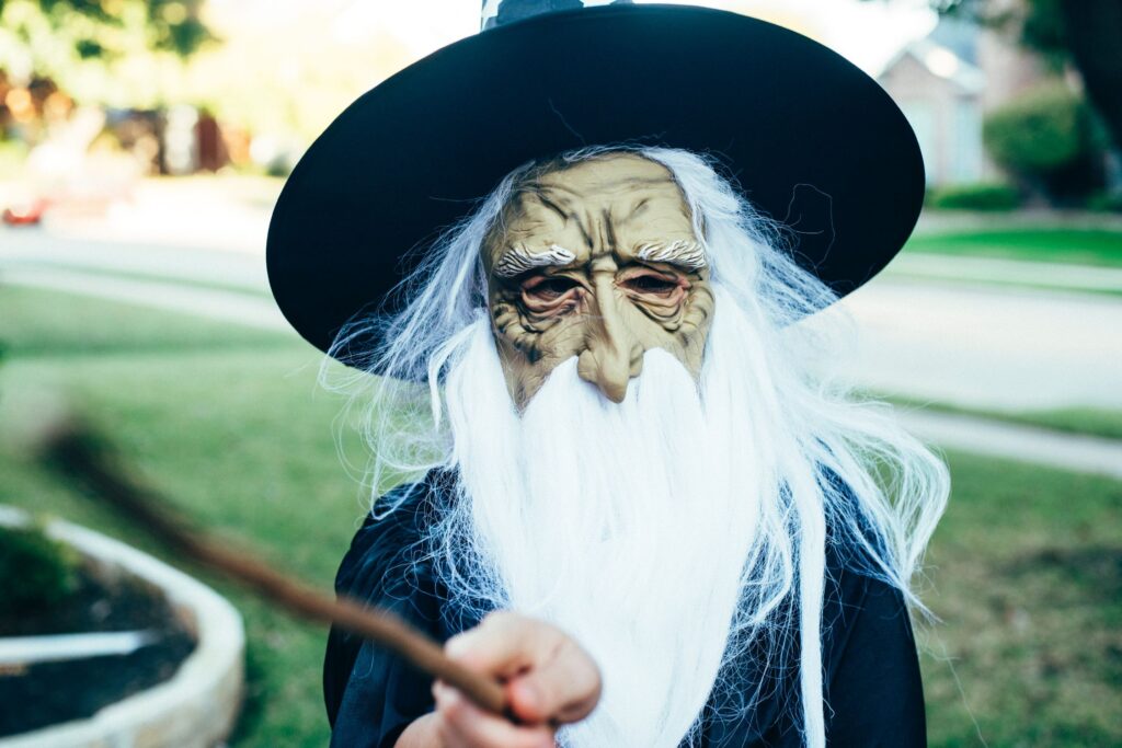 person in wizard mask holding a magic wand