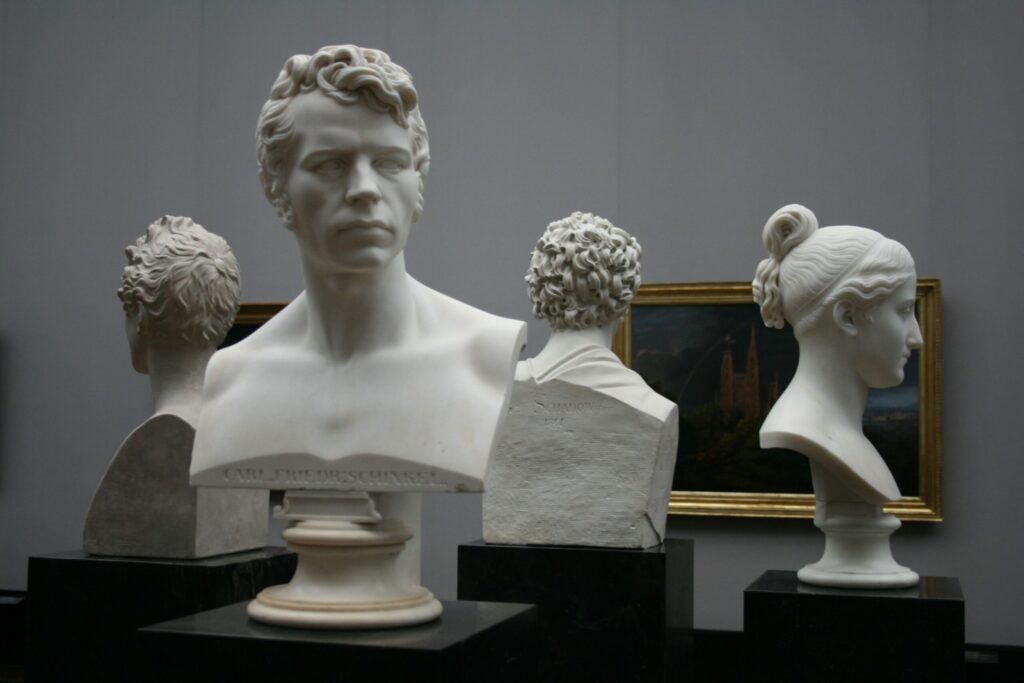 four busts on pedestals in a museum