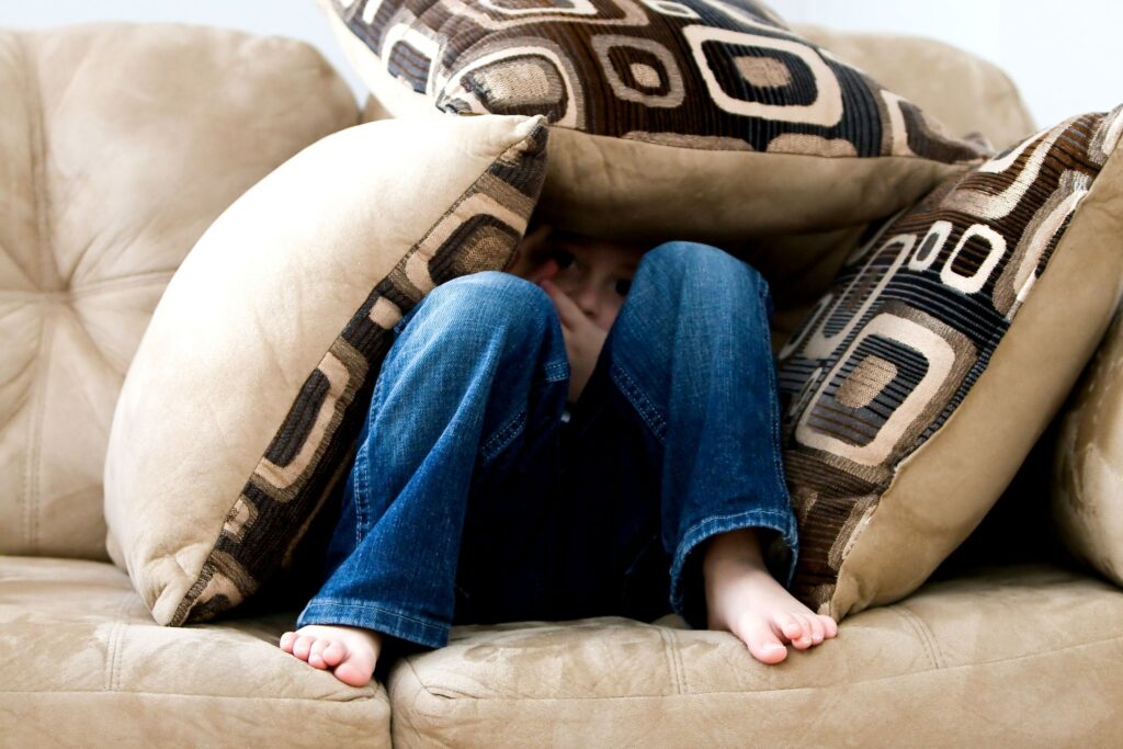 child hiding under pillows in fear
